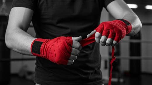 Pair of Sting hand wraps rolled neatly beside boxing gloves on a gym bench
