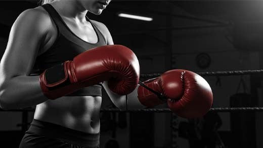 Female boxer wearing pink boxing gloves during training.