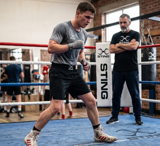 Beginner boxer demonstrating proper boxing footwork stance and movement techniques in a gym